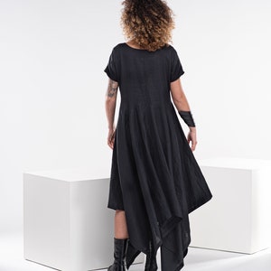 May include: A black linen dress with a short sleeve and a high low hemline. The dress is asymmetrical and has a flowing silhouette.