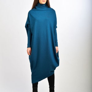 May include: A teal blue long-sleeved dress with a high neck and a loose, flowing fit. The dress is made of a soft, comfortable fabric and has a relaxed, casual style.