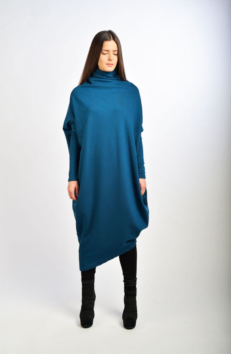 May include: A teal blue long-sleeved dress with a high neck and a loose, flowing fit. The dress is made of a soft, comfortable fabric and has a relaxed, casual style.