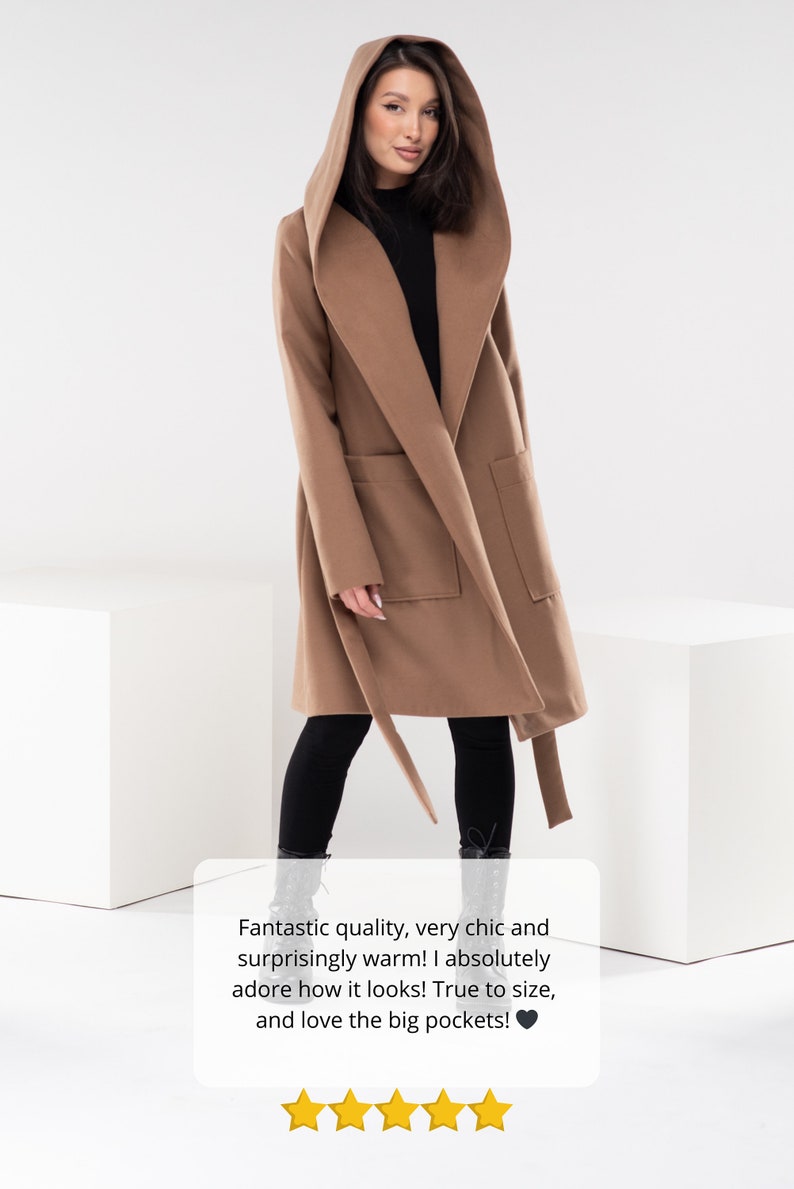 May include: A brown hooded wrap coat with a tie belt and large pockets. The coat is worn by a person standing on a white surface. The text "Fantastic quality, very chic and surprisingly warm! I absolutely adore how it looks! True to size, and love the big pockets!" is displayed below the image. Five yellow stars are displayed below the text.