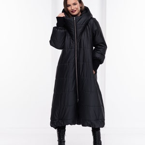 May include: A long black puffer coat with a high collar and a zip fastening. The coat has a quilted design and a slightly flared shape.