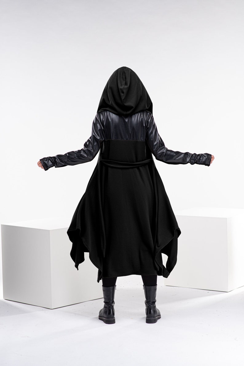 May include: A black hooded coat with a long, flowing design and a belt. The coat has leather accents on the sleeves and a unique asymmetrical hem.