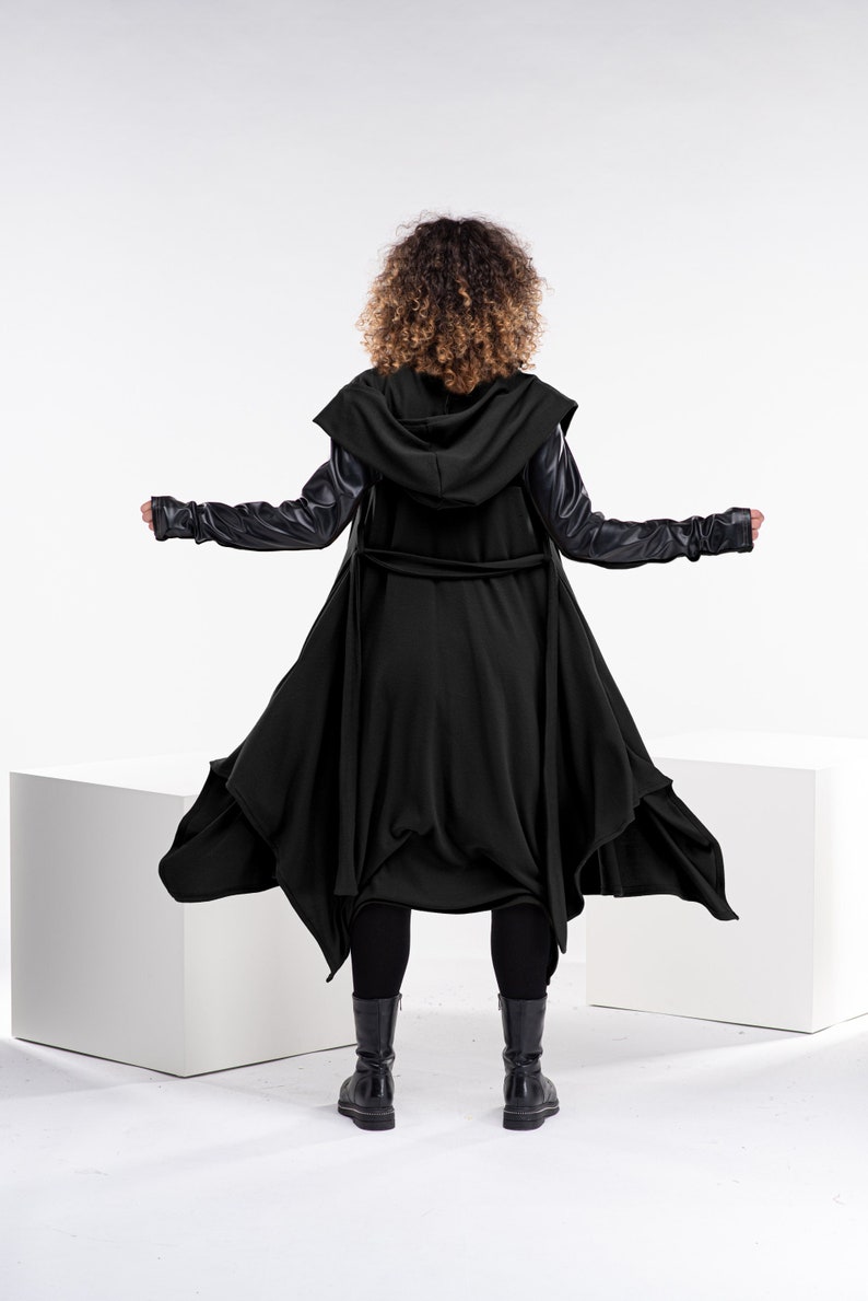 May include: A black hooded jacket with long sleeves and a flowing hemline. The jacket has a belt at the waist and is made of a soft, comfortable fabric.