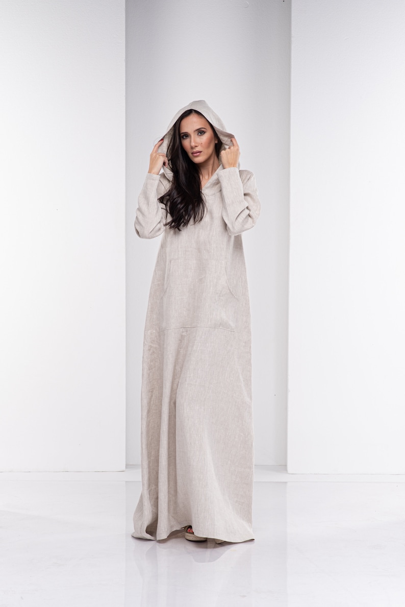 May include: A long, beige linen dress with a hood. The dress has a relaxed fit and a simple design.