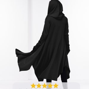 May include: A black hooded long jacket with a flowing design. The jacket is warm, comfortable, stylish, and casual. It's so hard to find a long jacket that is warm, comfortable, stylish, and casual. It's amazing to have an option beyond loose-knit cardigans and trenchcoats. This is exactly what I was looking for, only better. I got a bunch of compliments my first day wearing it. It's so comfortable and I can wear it with anything. I couldn't be happier.