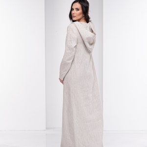 May include: A long, beige linen dress with a hood. The dress has a relaxed fit and is made of a lightweight fabric.