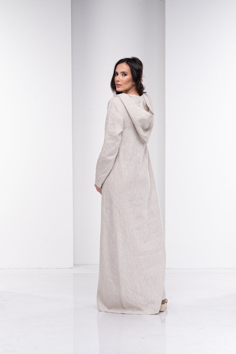 May include: A long, beige linen dress with a hood. The dress has a relaxed fit and is made of a lightweight fabric.