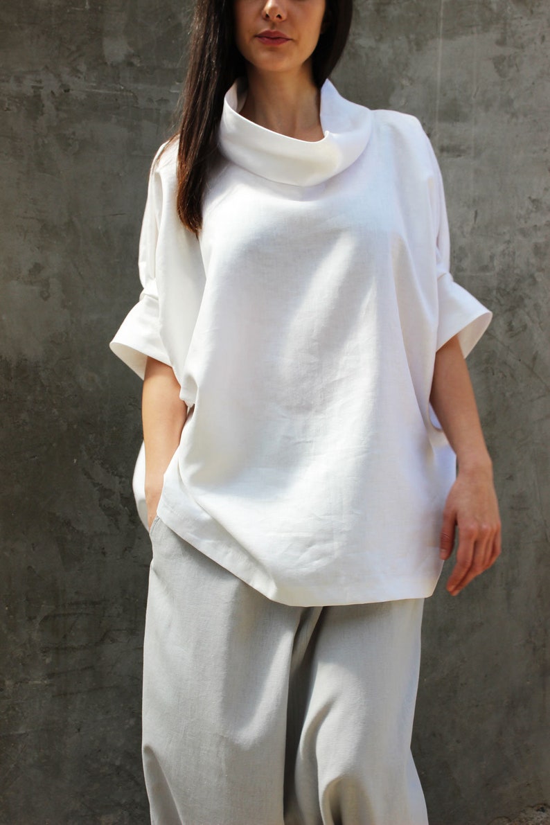 May include: A white linen top with a cowl neck and short sleeves. The top is loose fitting and has a relaxed silhouette.