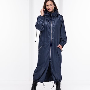 May include: A long navy blue hooded jacket with a zipper closure and two pockets. The jacket has a drawstring at the waist and a cinched hood.