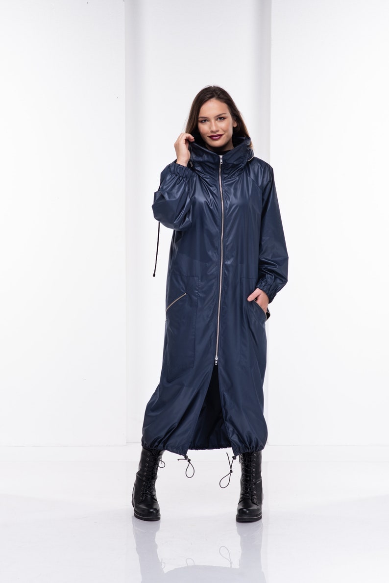 May include: A long navy blue hooded jacket with a zipper closure and two pockets. The jacket has a drawstring at the waist and a cinched hood.