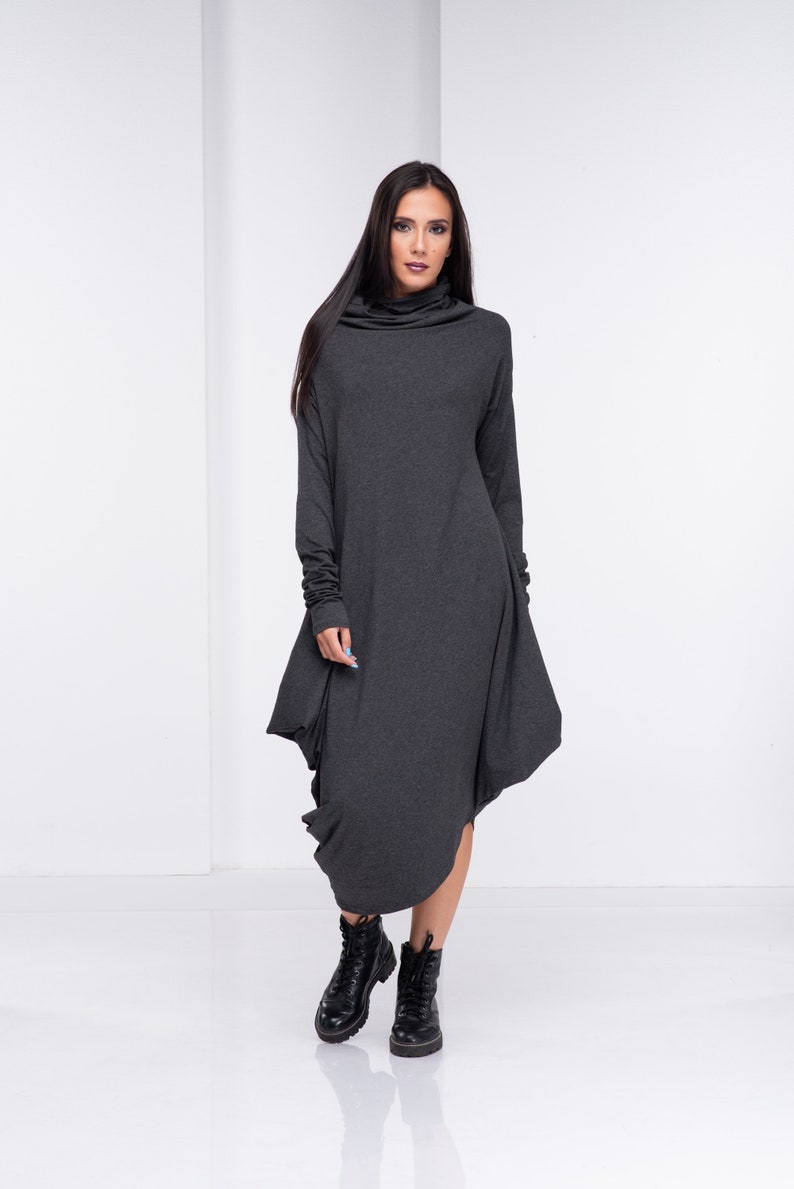 May include: A charcoal gray long-sleeved dress with a cowl neck and a loose, asymmetrical hem. The dress is made of a soft, comfortable fabric and has a relaxed fit.