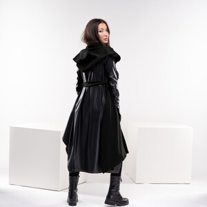May include: A black hooded coat with a long, flowing design. The coat has a belt and is made of a shiny, leather-like material.