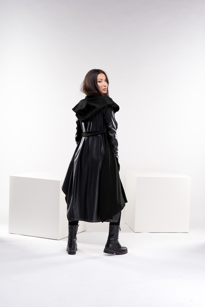 May include: A black hooded coat with a long, flowing design. The coat has a belt and is made of a shiny, leather-like material.