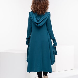 Könnte beinhalten: Ein langärmliger Kapuzencardigan in Tealblau mit einem langen, fließenden Saum. Der Cardigan ist aus einem weichen, bequemen Stoff gefertigt und hat eine lockere Passform.