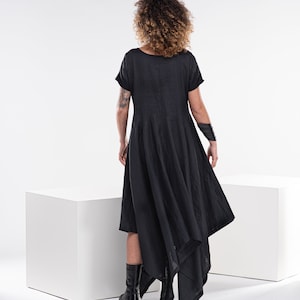 Pu&ograve; includere: Un abito in lino nero con maniche corte e un orlo alto e basso. L'abito &egrave; asimmetrico e ha una silhouette fluida.