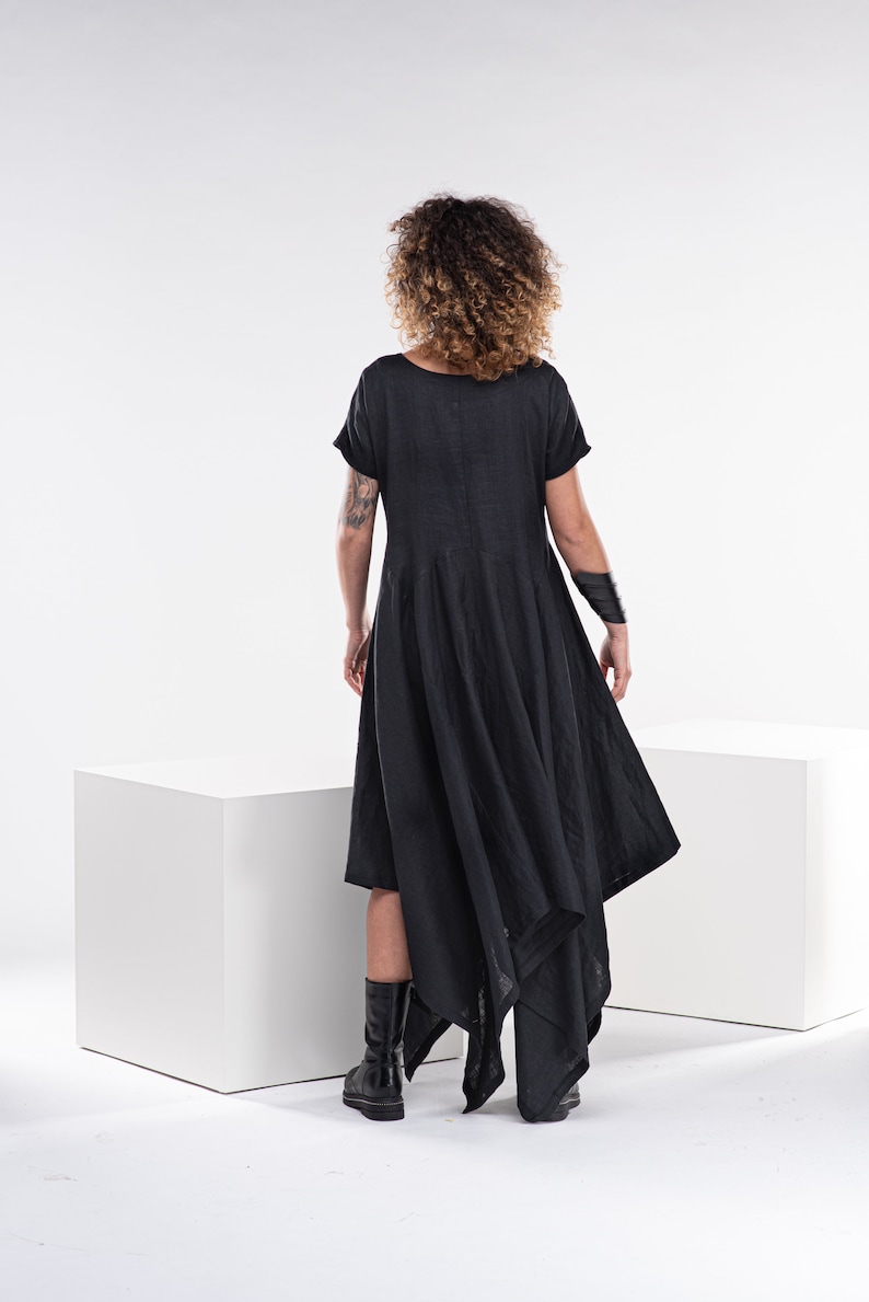 Pu&ograve; includere: Un abito in lino nero con maniche corte e un orlo alto e basso. L'abito &egrave; asimmetrico e ha una silhouette fluida.