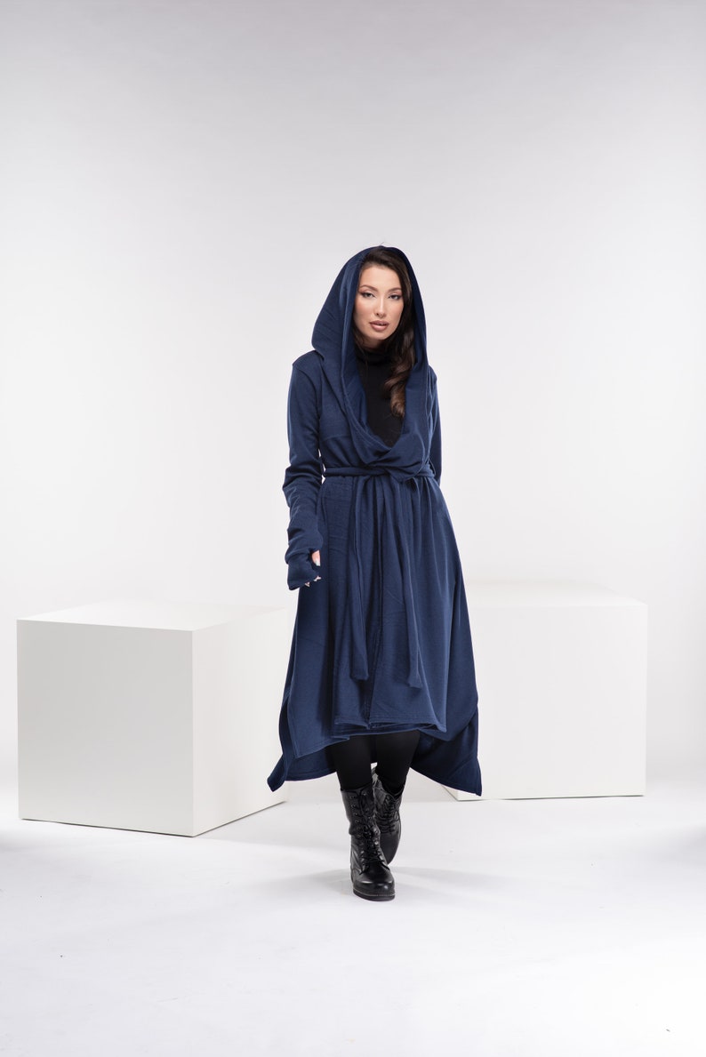 May include: A long, navy blue hooded cardigan with a tie belt and thumbholes. The cardigan is made of a soft, comfortable fabric and has a relaxed fit.