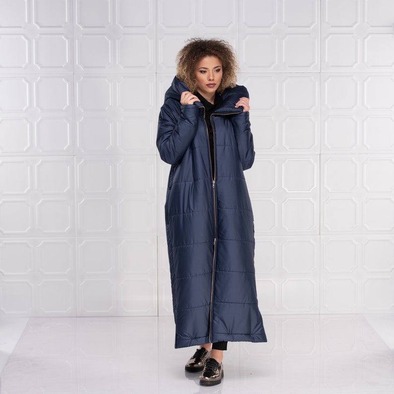Long hooded puffer jacket with asymmetrical design in quilted 150g fabric, featuring a double front zipper, side pockets, and viscose lining. Edgy, cyberpunk-inspired style for a bold, modern winter look. Shown in dark blue color here.