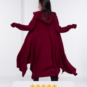 May include: A burgundy hooded cloak with long sleeves and a flowing design. The cloak is made of a soft, comfortable fabric and has a relaxed fit.