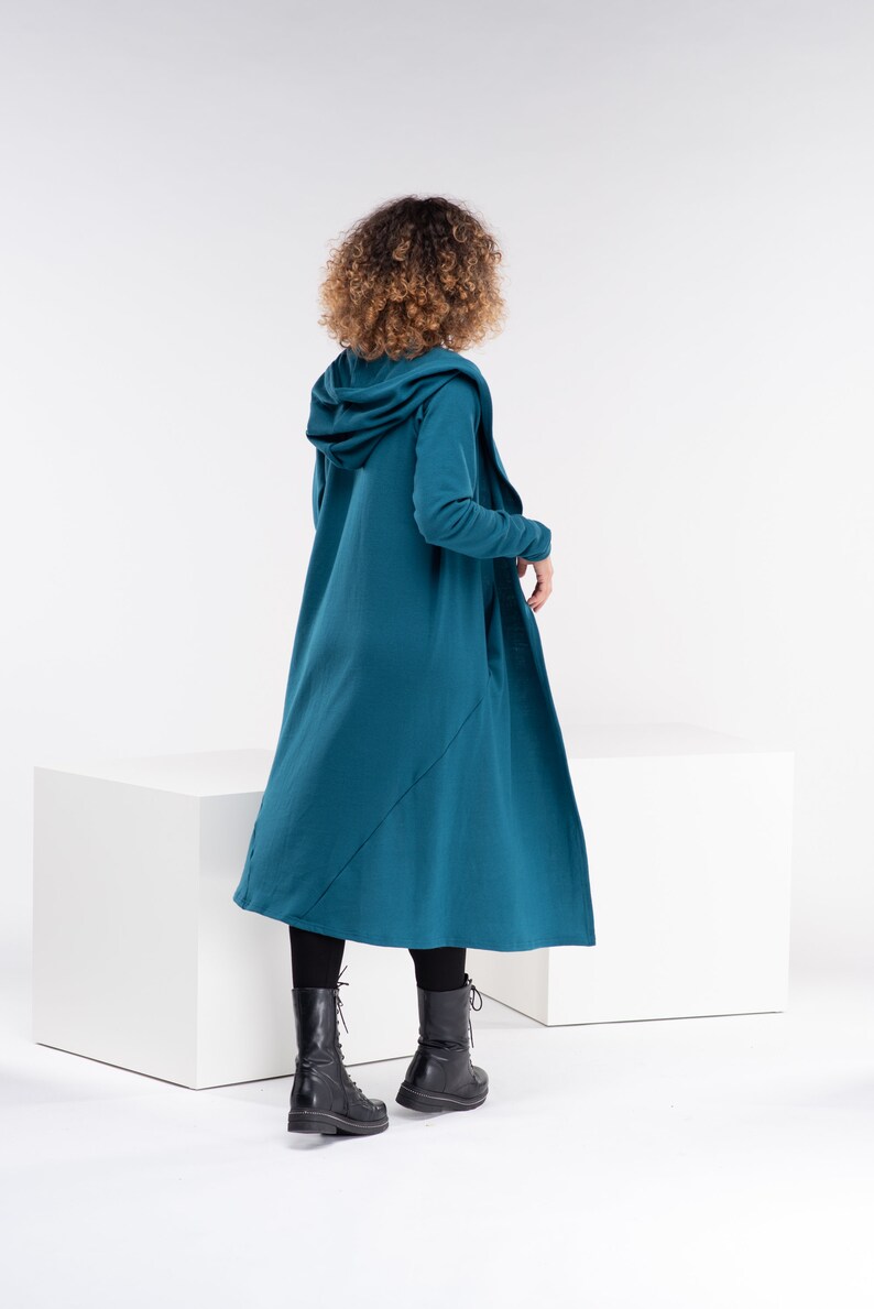 Pu&ograve; includere: Un cardigan color teal con cappuccio, maniche lunghe e un design lungo e fluido. Il cardigan &egrave; realizzato in un tessuto morbido e confortevole e ha una vestibilit&agrave; rilassata.