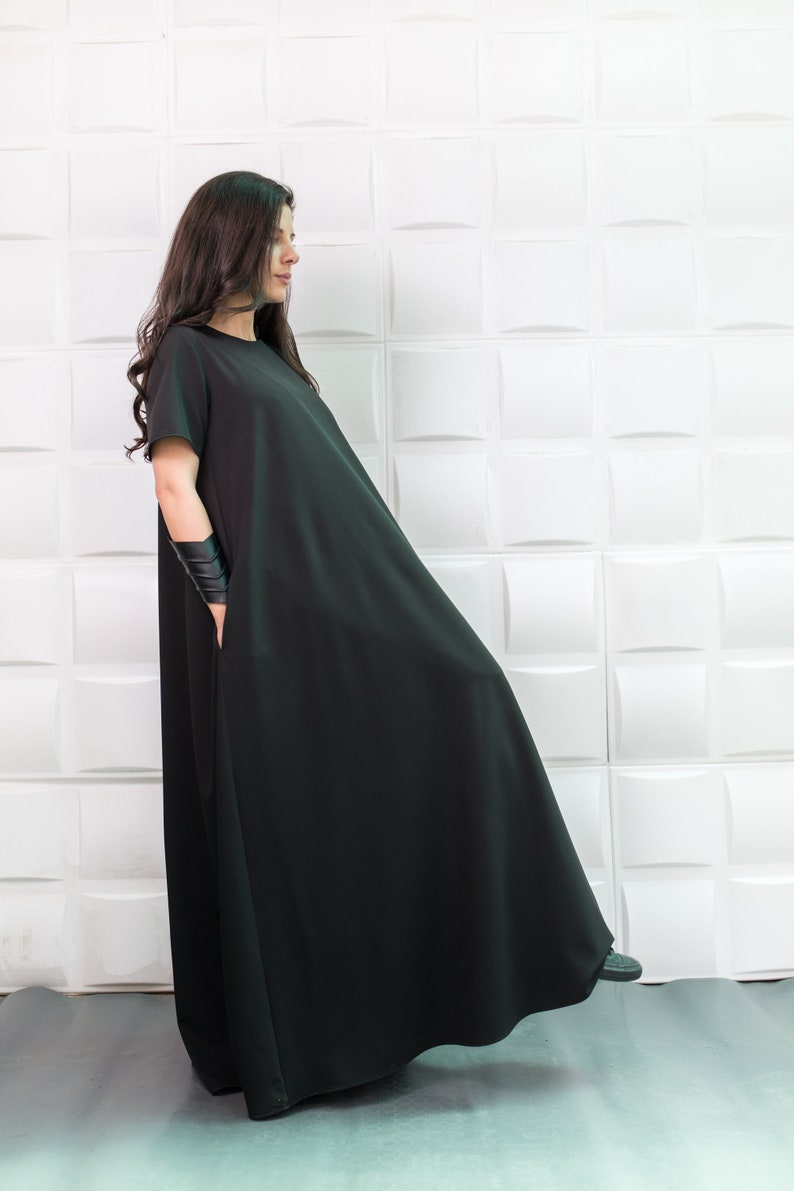 K&ouml;nnte beinhalten: Eine Frau tr&auml;gt ein schwarzes Maxikleid mit kurzen &Auml;rmeln. Das Kleid hat eine lockere, flie&szlig;ende Passform und ist aus einem weichen, bequemen Stoff.