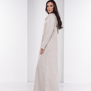 May include: A long, beige linen dress with a hood. The dress has a relaxed fit and a simple design.