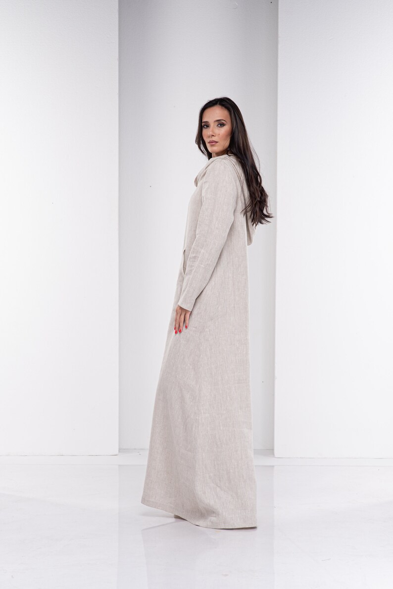 May include: A long, beige linen dress with a hood. The dress has a relaxed fit and a simple design.