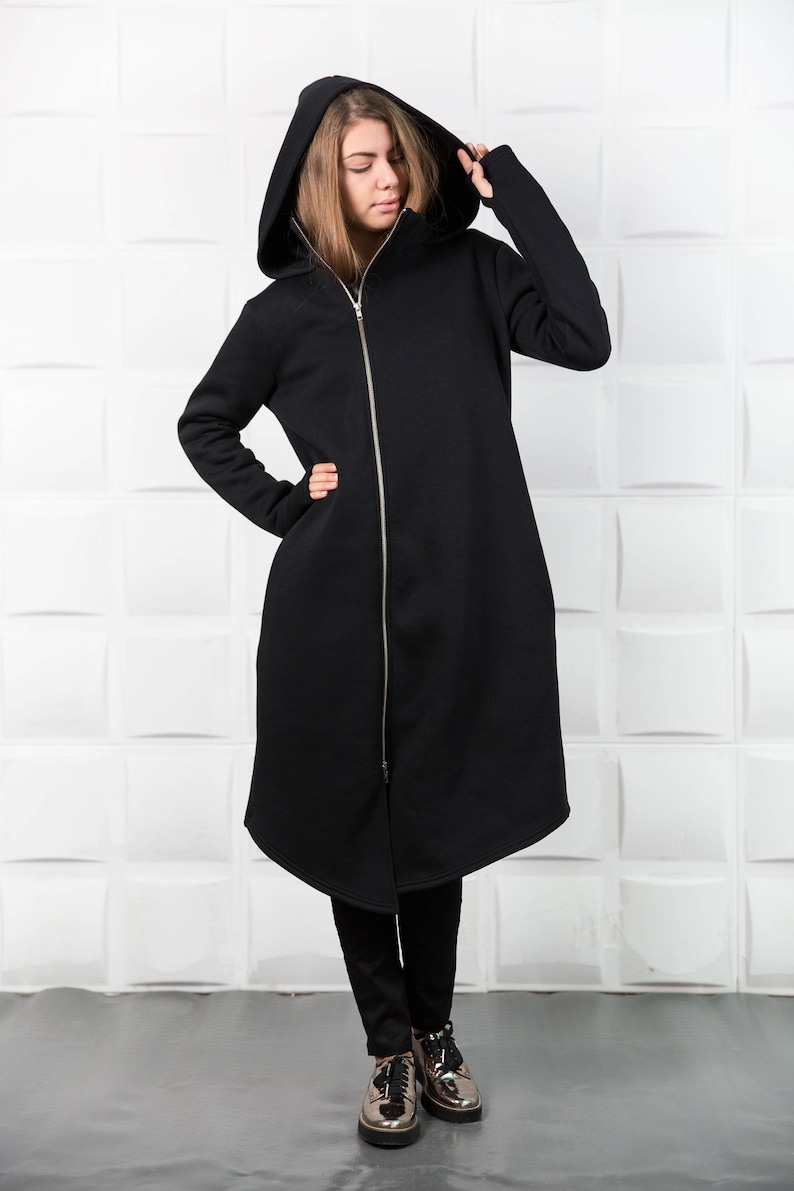 May include: A long black hooded sweatshirt with a zipper closure. The sweatshirt has a long, flowing design and is made of a soft, comfortable fabric.