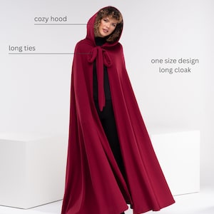 May include: A long, burgundy red cloak with a cozy hood and long ties. The cloak is one size and has a simple design.