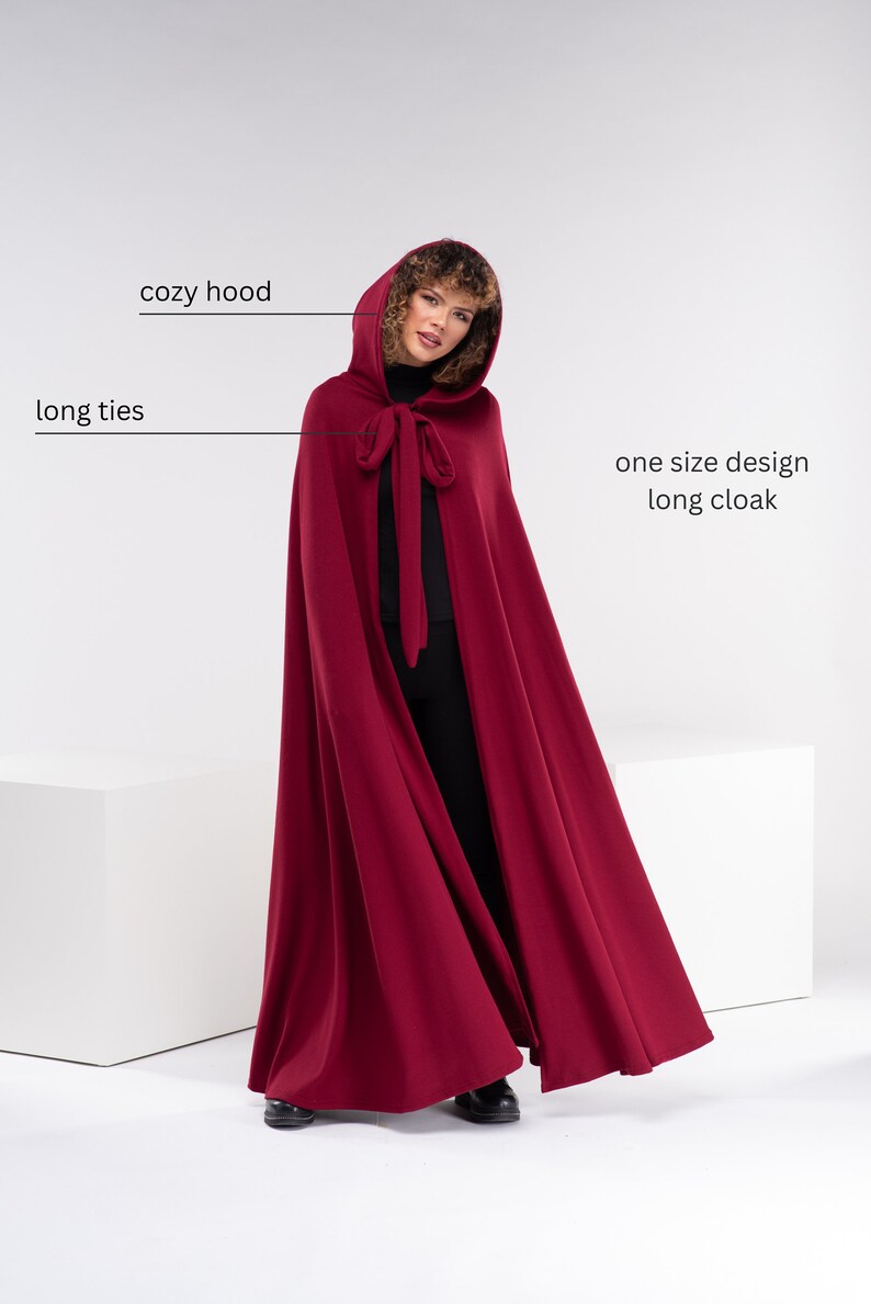 May include: A long, burgundy red cloak with a cozy hood and long ties. The cloak is one size and has a simple design.