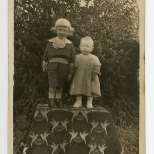 photo vintage 'On a Pedestal' hantant rppc format image de deux enfants posant sur un piédestal décoratif