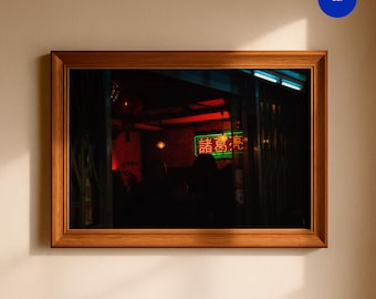 Könnte beinhalten: Ein rechteckiger Holzrahmen mit einem dunklen Foto eines schwach beleuchteten Innenraums. Das Bild zeigt ein leuchtendes Neonschild mit roten und grünen chinesischen Schriftzeichen, warme Hängeleuchten und die Silhouetten von Personen im Schatten.