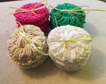 May include: Four crocheted round boxes with yellow ribbon tied around them. The boxes are in pink, green, beige, and white.