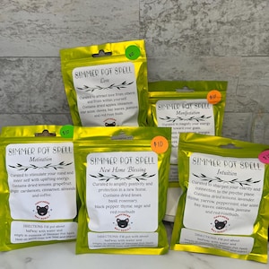May include: Several bright yellow Simmer Pot Spell pouches with various labels. The labels include text such as "Love", "Motivation", and "New Home Blessing". Each pouch has a price tag of $10. The pouches contain dried herbs and botanicals.