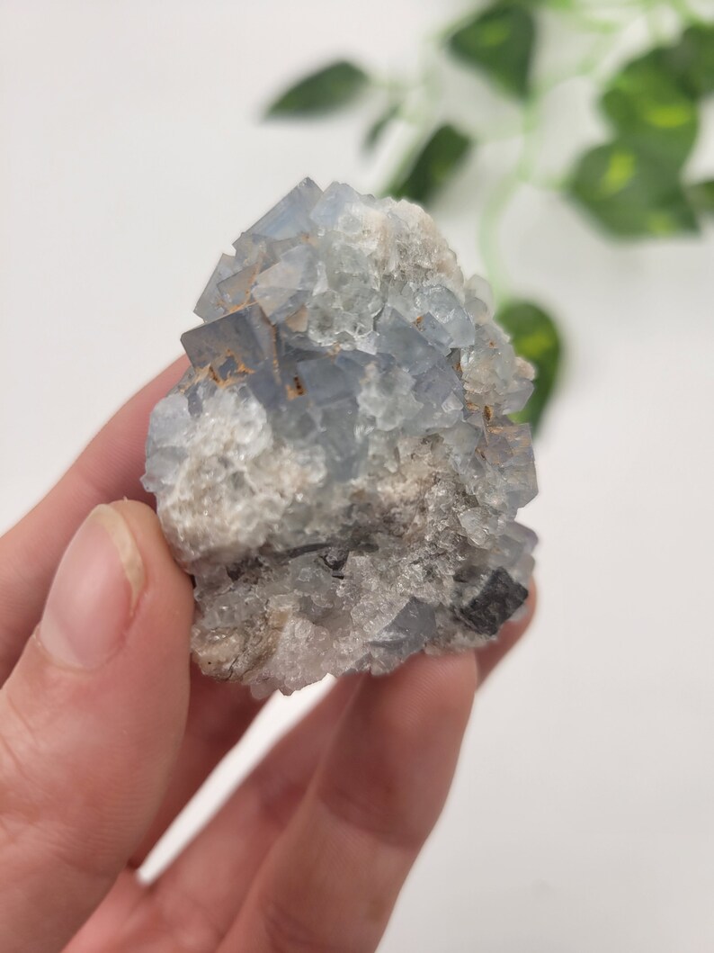 May include: A cluster of blue fluorite crystals with a rough, natural texture. The crystals are clustered together in a pyramid shape, with some smaller crystals surrounding the larger ones.
