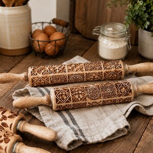 May include: Three wooden rolling pins featuring intricate, laser-engraved geometric and floral patterns across their cylindrical surfaces. Each tool includes smooth, light-colored wooden handles on both ends, designed for rolling dough with precision.