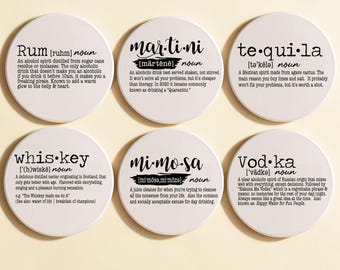 May include: A set of six round white ceramic coasters, each featuring black printed text defining a specific alcoholic beverage: Rum, Martini, Tequila, Whiskey, Mimosa, and Vodka. Each coaster includes the word, phonetic pronunciation, and a humorous definition.
