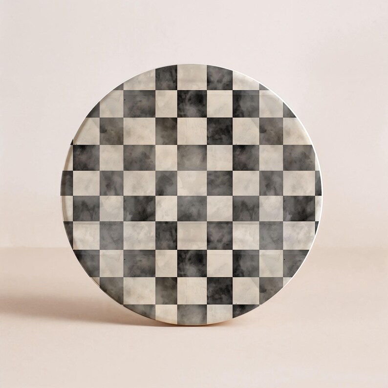 Op de afbeelding: Een ronde onderzetter met een zwart, wit en grijs geblokt patroon. De onderzetter heeft een marmerachtige uitstraling, met een subtiel, rokerig effect in de vierkanten. Het ontwerp is een klassiek dambord, geschikt voor diverse interieurstijlen.