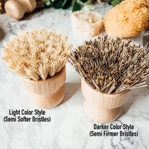 May include: Two wooden handled scrub brushes with natural bristles. The brush on the left has lighter coloured bristles and the brush on the right has darker coloured bristles. The text below the brushes reads "Light Color Style (Semi Softer Bristles)" and "Darker Color Style (Semi Firmer Bristles)".