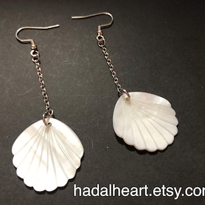 May include: A pair of drop earrings featuring white iridescent shell pendants suspended from silver-toned metal chains and fishhook ear wires. The text hadalheart.etsy.com is visible at the bottom of the image, showcasing the shell design.