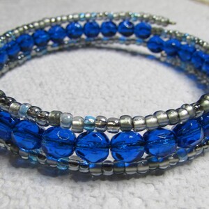 May include: A silver and blue beaded bracelet with multiple strands of beads. The bracelet is made with small silver beads and larger blue beads.