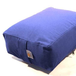 May include: A blue rectangular meditation cushion with a zipper. The cushion is made of fabric and has a label with the word "Iris" on it.