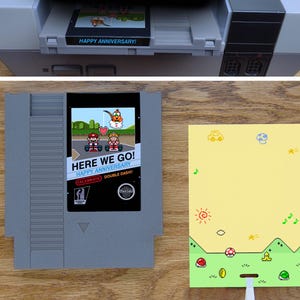 A greeting card is made from a reproduction NES cart with a glossy label. Art shows Mario and Peach ready to race with Lakitu holding a heart overhead in a scene from Mario Kart. A flat card pulls art from the title screen with items on the ground.