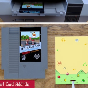 May include: An insert card add-on with a retro video game theme. The card features the text "1ST PLACE DAD HAPPY FATHER'S DAY!" and a pixelated graphic. A yellow card with a green border and cartoon graphics is also shown.