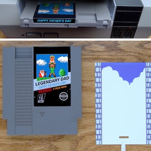 May include: A custom Nintendo Entertainment System (NES) game cartridge with a blue and white label that reads "Legendary Dad Happy Father's Day Celebrate A True Hero". The label features a pixelated image of a father and son in a video game style.