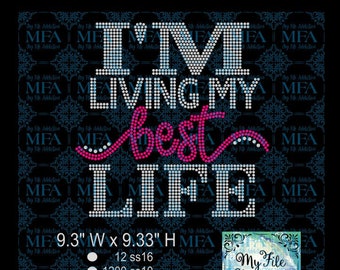 Pode incluir: Design de strass para uma camiseta ou outra roupa. O design diz "I'm Living My Best Life" em strass branco, rosa e azul. O design tem 9,3 polegadas de largura e 9,33 polegadas de altura. O design usa 12, 1200 e 317 strass nos tamanhos 16, 10 e 10, respectivamente. A contagem total de strass é 1529.