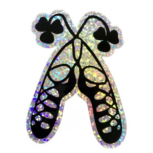 May include: A pair of black Irish dance shoes with a shamrock design on a holographic background.