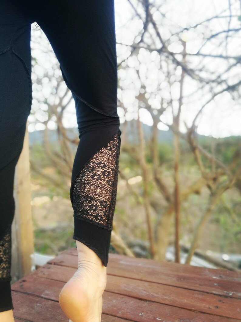 May include: Black leggings with a lace panel on the lower leg. The leggings are worn by a person standing on a wooden deck.