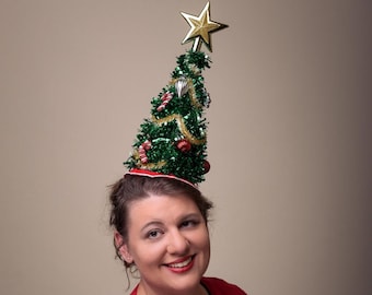 May include: A woman wearing a red sweater and a green Christmas tree hat with a gold star on top. The text "Jezebel's Fascination" is written in pink letters at the bottom of the image.