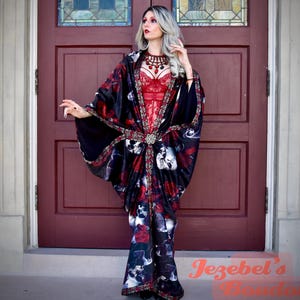 Könnte beinhalten: Ein schwarzer Kimono mit Totenkopf- und Rosenmuster, kombiniert mit einem roten Spitzenmieder. Der Kimono ist mit roten Rosen und Totenkopfmotiven verziert. Eine rote Perlenkette ist ebenfalls zu sehen.